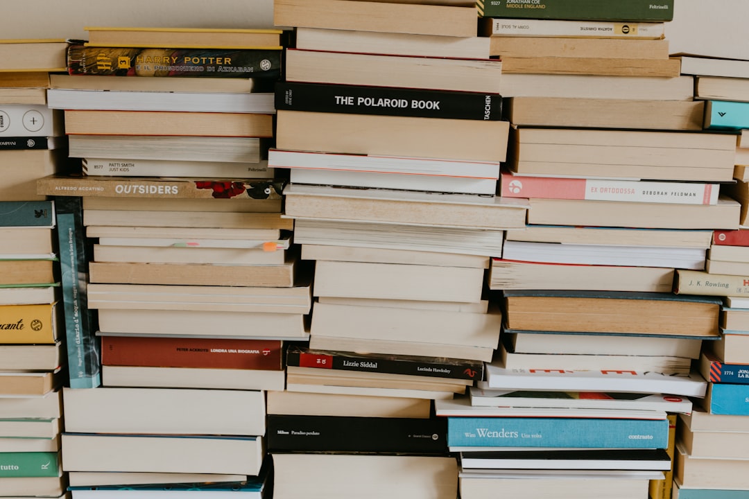 a-pile-of-books-sitting-on-top-of-a-wall-pjpe-zlqvnm